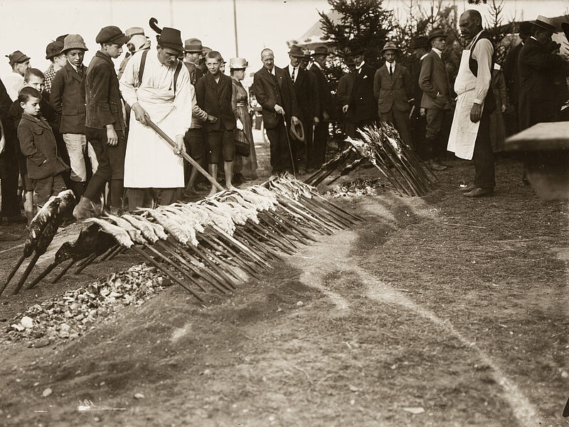 Philipp Kester, Münchner Oktoberfest – Mann beim Steckerfisch-Braten mit hungrigen Zuschauern, 1921