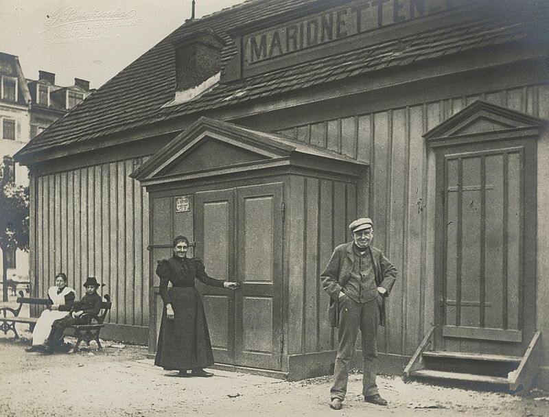 Münchner Marionettentheater, Georg Pettendorfer, Foto "J. L. Schmid und B. Klinger vor dem Theater am Maffeianger", um 1890