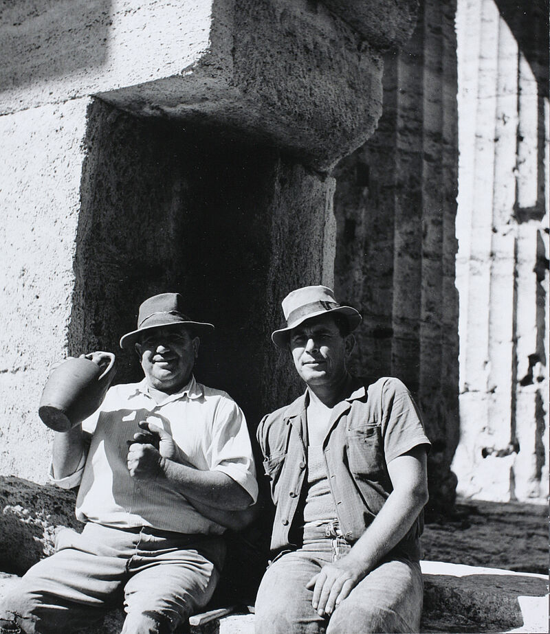 Paestum. Zwei Arbeiter auf den Stufen des Neptun-Tempels mit einem Krug voll Landwein, 1950