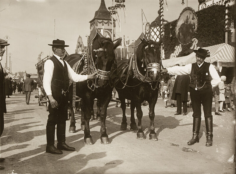 Philipp Kester, Münchner Oktoberfest – Zwei Kutscher posieren neben den Pferden ihres Bierwagengespannes, 1932