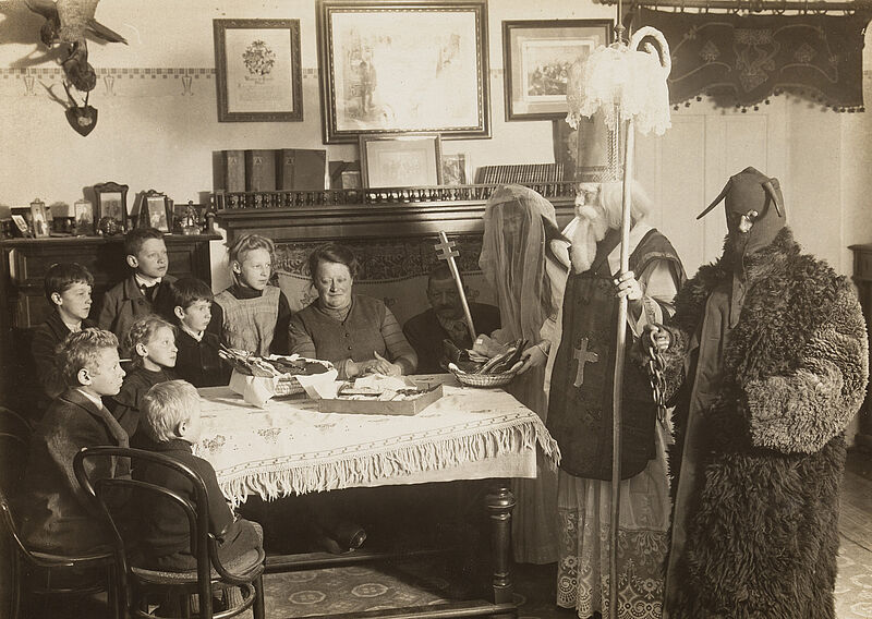 Philipp Kester, Nikolausfeier in Tirol – Nikolaus mit Krampus und Engel vor einer Kinderschar, um 1922