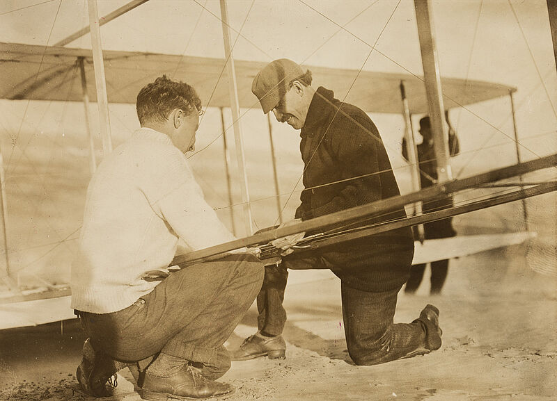 Philipp Kester, Orville Wright und Alec Ogilvie bei der Arbeit an einem Flugzeug – Bei einem der ersten Versuche Wrights mit einem motorlosen Flugzeug an der Küste bei Kill Devil Hill, North Carolina, um 1911