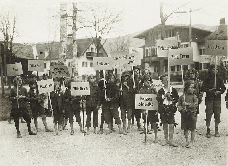 Philipp Kester, Oberammergauer Passionsspiele – Kinder mit Schildern der jeweiligen Pensionen warten auf ankommende Gäste, 1922
