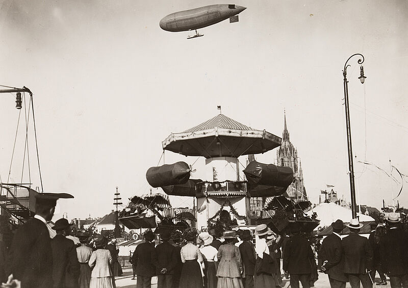 Philipp Kester, Münchner Oktoberfest – Ein Luftschiffkarussell und darüber sein Vorbild, das Luftschiff "Parseval", um 1910