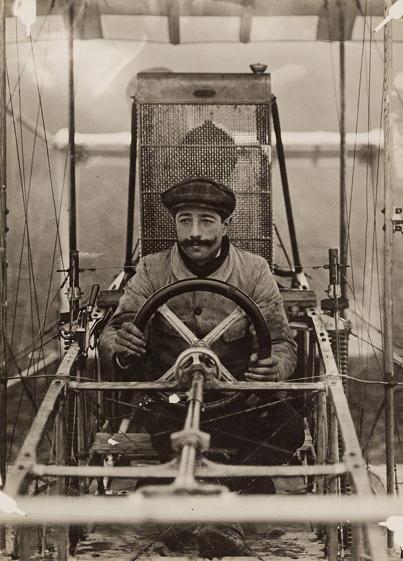 Philipp Kester, Flugschule Henri Farman – Der Flieger Forest am Steuerrad einer Maschine in Mourmelon, England, 1910